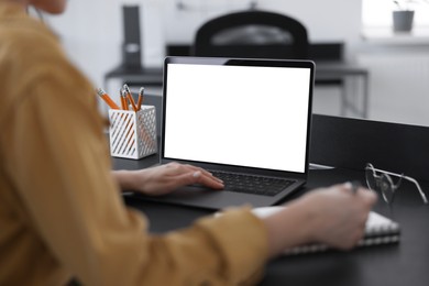 Woman taking notes during webinar at table indoors, closeup