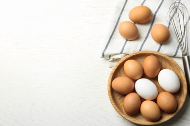 Photo of Chicken eggs on white wooden table, flat lay. Space for text