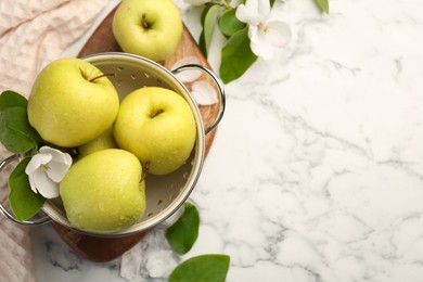 Photo of Colander with fresh apples and beautiful spring blossoms on white marble table, flat lay. Space for text