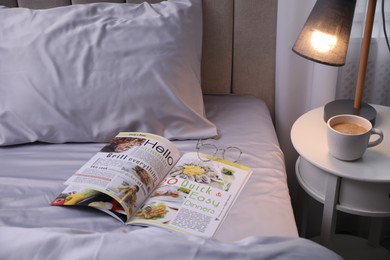 Photo of Magazine on bed with soft silky bedclothes in room