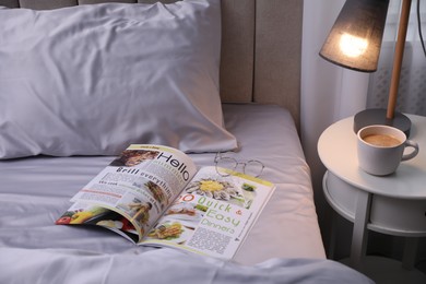 Magazine on bed with soft silky bedclothes in room