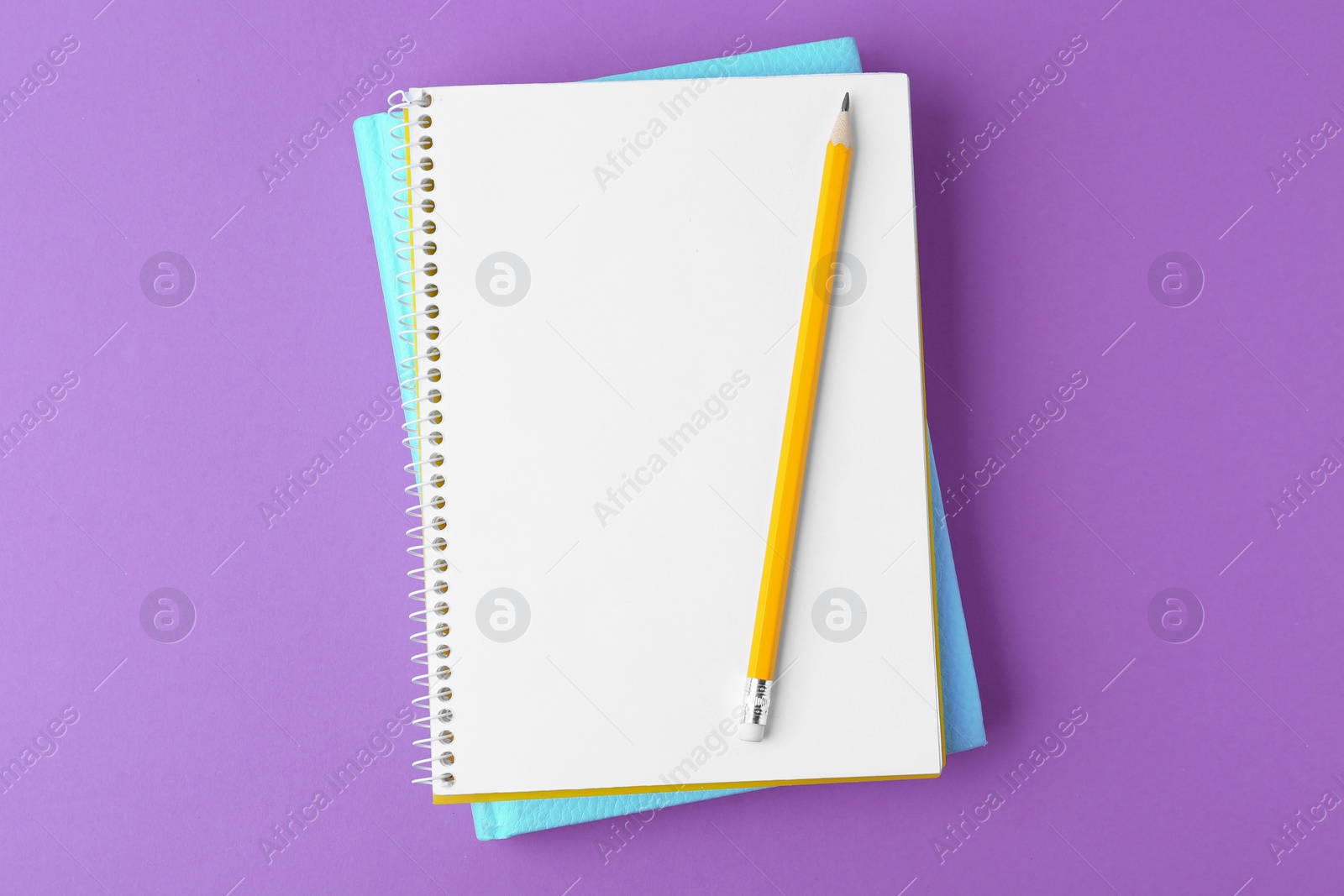 Photo of Notebooks with pencil on purple background, top view