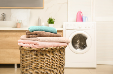 Photo of Wicker basket with laundry and washing machine in bathroom