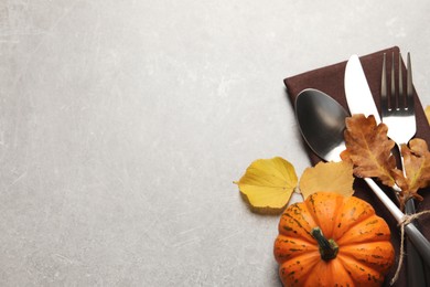 Photo of Cutlery, autumn leaves and pumpkin on light grey table, flat lay. Space for text