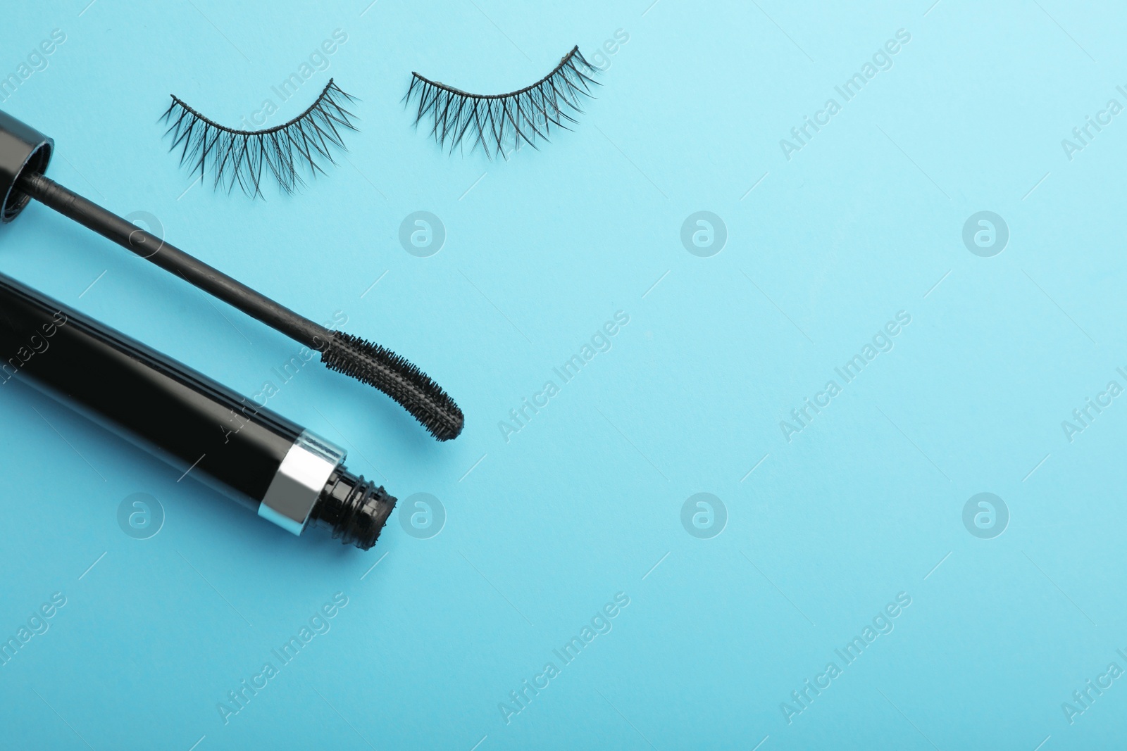 Photo of Flat lay composition of black mascara and false eyelashes on color background, space for text