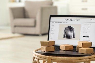 Photo of Online store. Laptop and mini parcels on table indoors, space for text