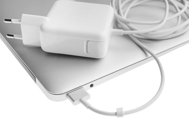 Laptop and charger on white background, closeup. Modern technology