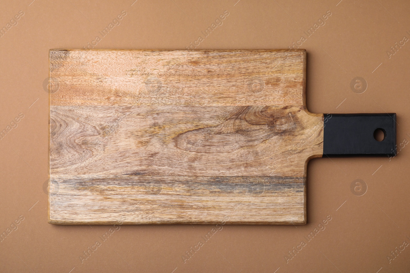 Photo of One wooden board on light brown background, top view