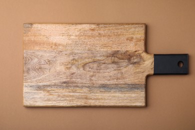 One wooden board on light brown background, top view