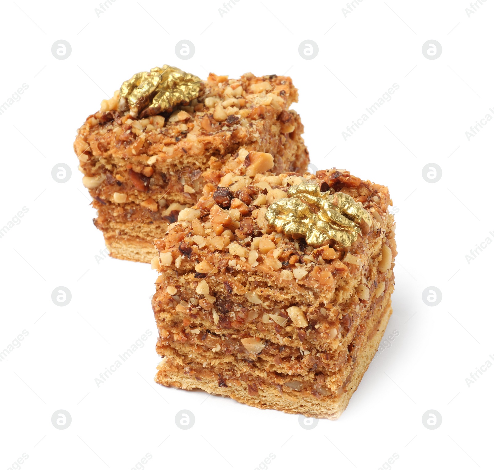 Photo of Pieces of layered honey cake with walnuts on white background