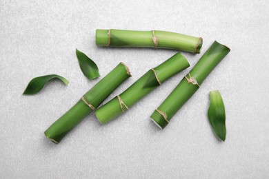 Photo of Pieces of beautiful green bamboo stems on light table, flat lay