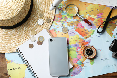 Photo of Different items on world map, flat lay. Travel during summer vacation