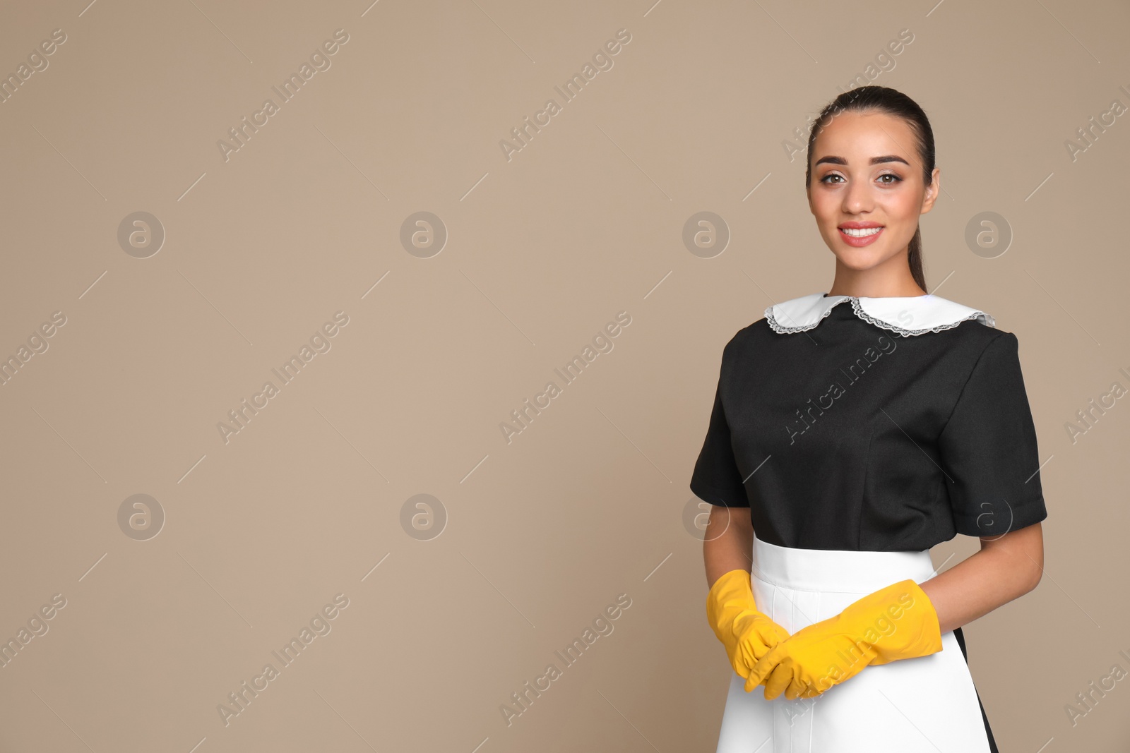 Photo of Portrait of young chambermaid in tidy uniform on color background