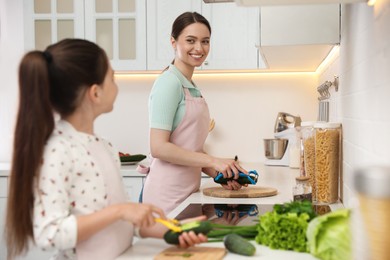 Photo of Mother and daughter peeling vegetables at kitchen counter