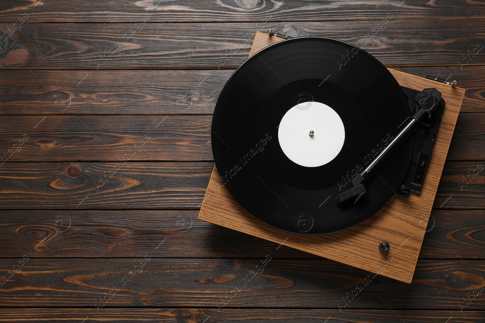 Photo of Turntable with vinyl record on wooden background, top view. Space for text