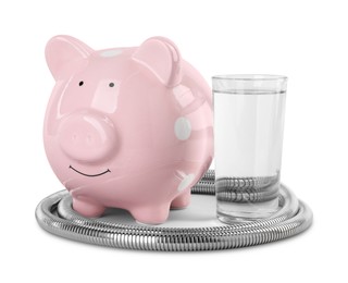Photo of Water scarcity concept. Piggy bank, shower hose and glass of drink isolated on white