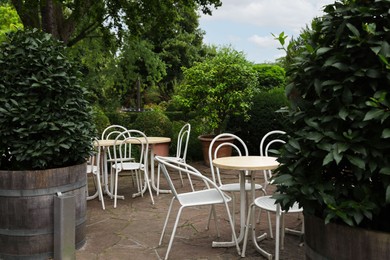 Photo of Beautiful garden with tables, chairs and green plants