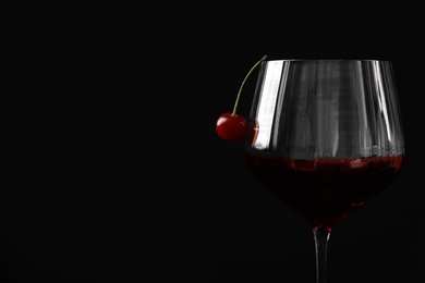 Photo of Delicious cherry wine with ripe juicy berries on black background, closeup. Space for text