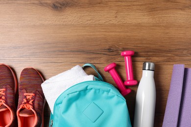 Photo of Flat lay composition with backpack and different sports equipment on wooden surface. Space for text