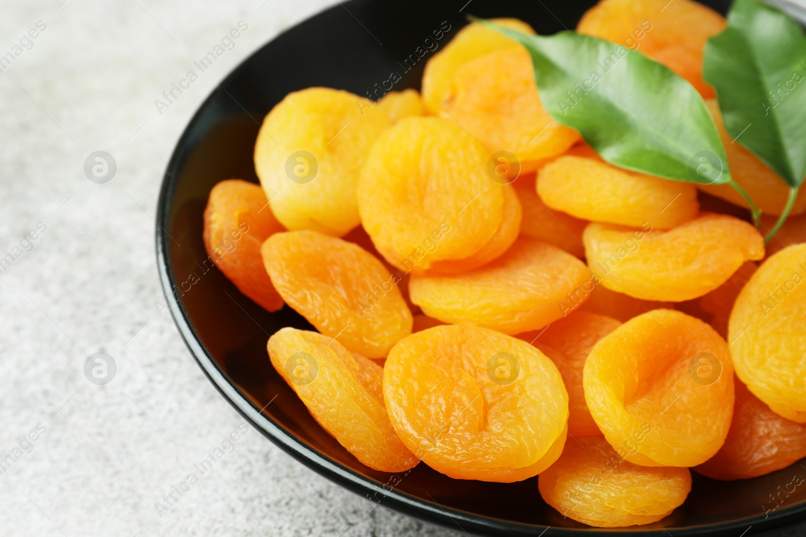 Photo of Plate of tasty apricots on grey table, closeup. Dried fruits