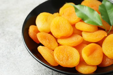 Plate of tasty apricots on grey table, closeup. Dried fruits
