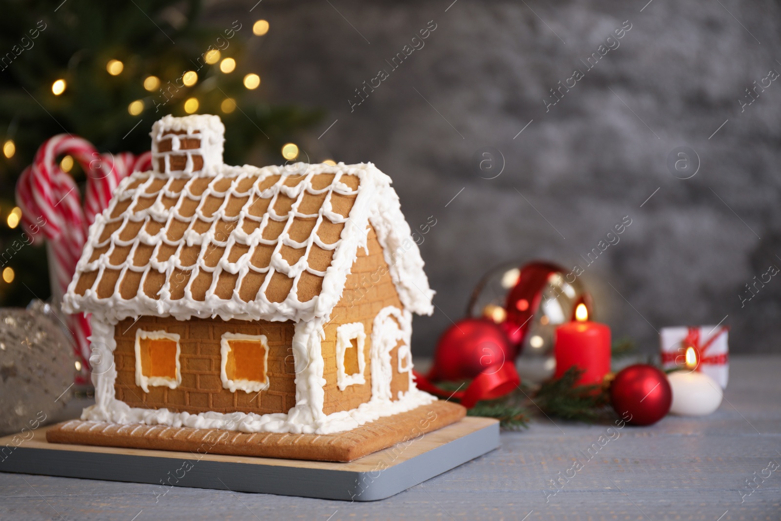 Photo of Beautiful gingerbread house decorated with icing on grey wooden table