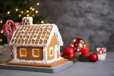 Photo of Beautiful gingerbread house decorated with icing on grey wooden table
