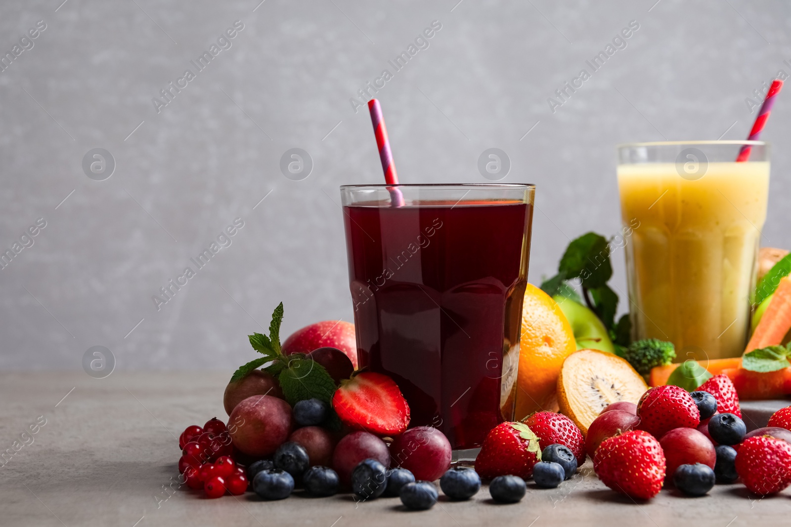 Photo of Delicious juice and fresh ingredients on grey table. Space for text