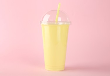 Photo of Plastic cup of tasty smoothie on pink background