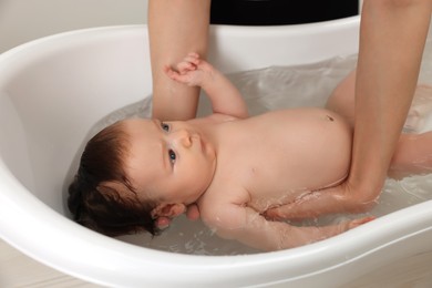 Mother bathing her little baby in bathtub, closeup