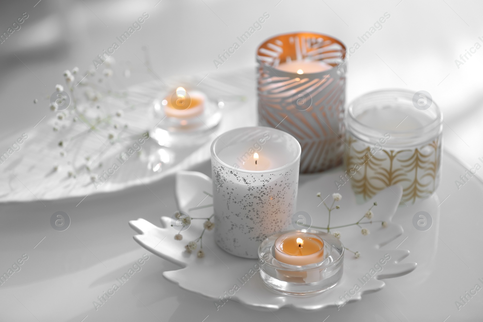 Photo of Burning candles in beautiful holders and flowers on table indoors