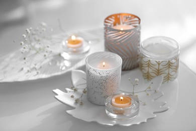 Burning candles in beautiful holders and flowers on table indoors