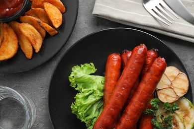 Delicious grilled sausages and vegetables on grey table, flat lay