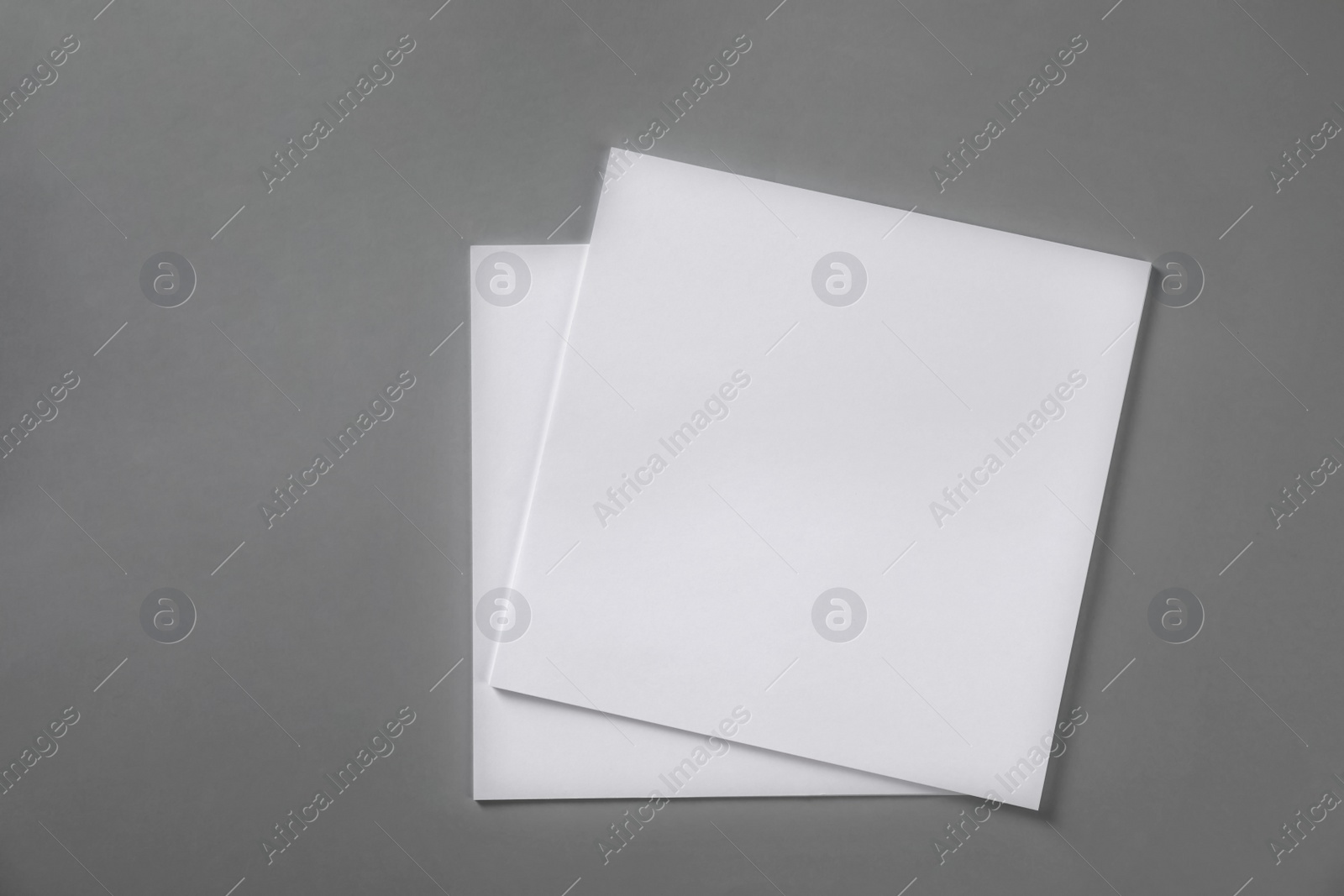 Photo of Stack of blank paper sheets for brochure on light grey background, top view