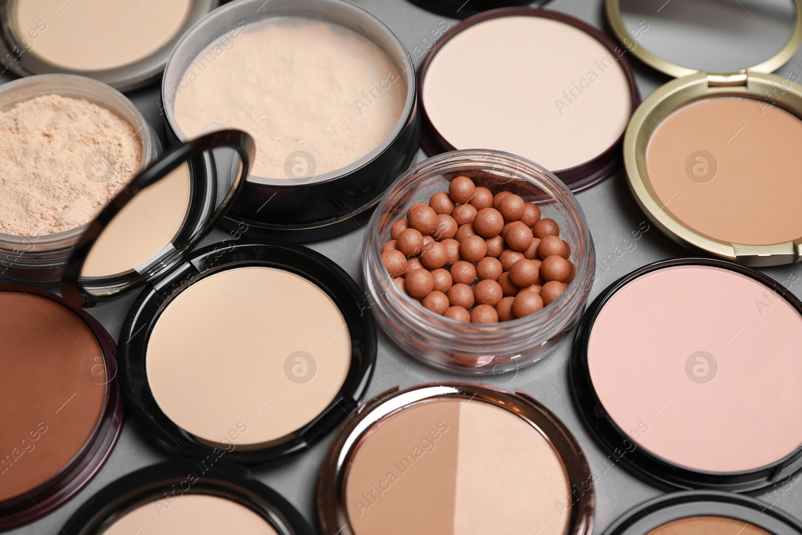 Photo of Different face powders on grey background, closeup