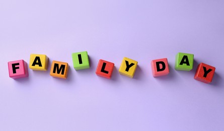 Photo of Colorful cubes with text Family Day on violet background, flat lay
