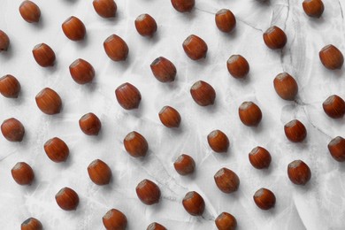 Tasty hazelnuts on light marble table, flat lay