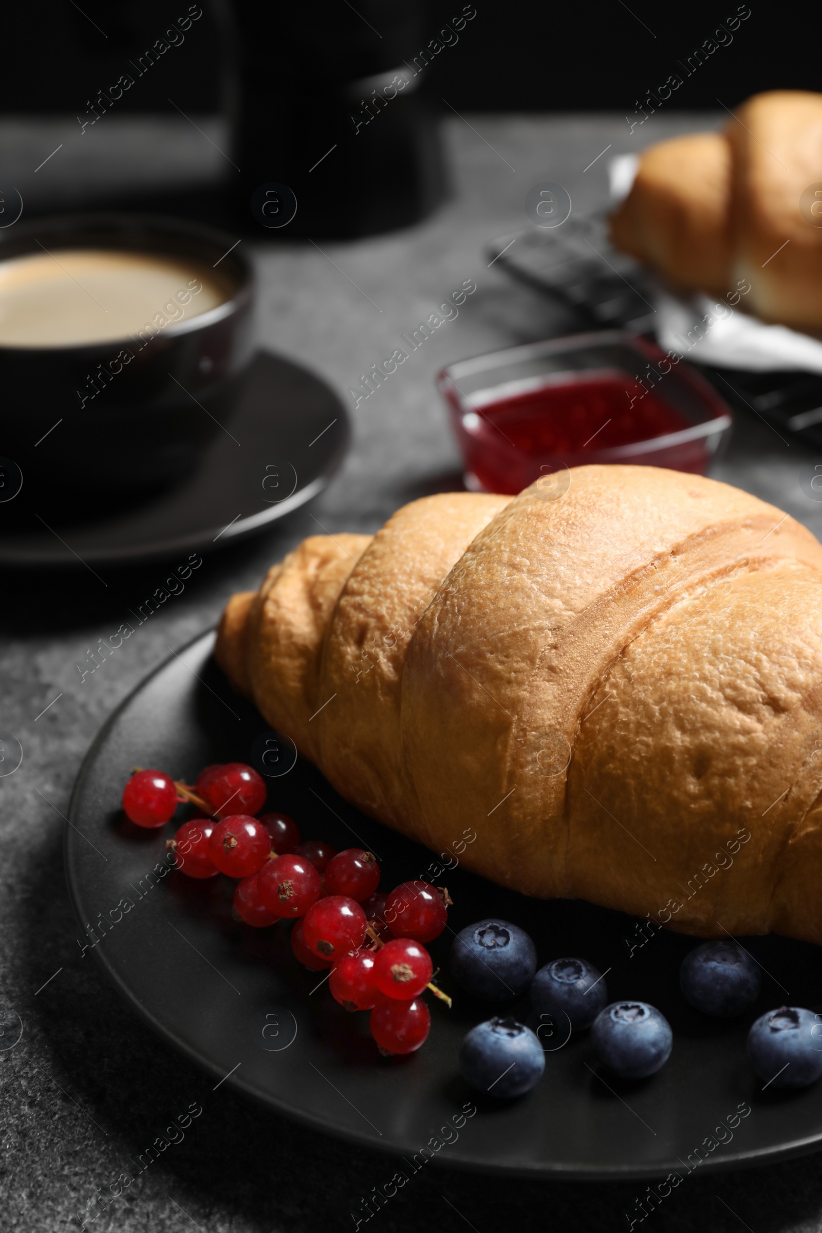 Photo of Plate with fresh crispy croissant and berries on grey table, closeup