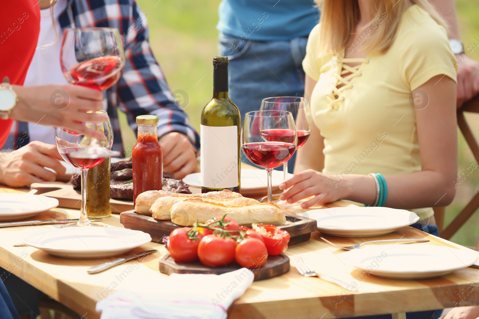 Photo of Young people having picnic at table outdoors