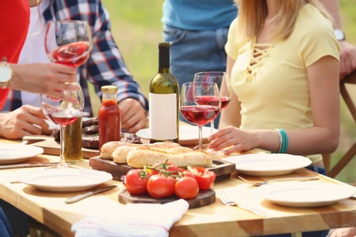 Photo of Young people having picnic at table outdoors