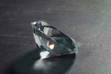 Photo of Beautiful dazzling diamond on black textured background, closeup
