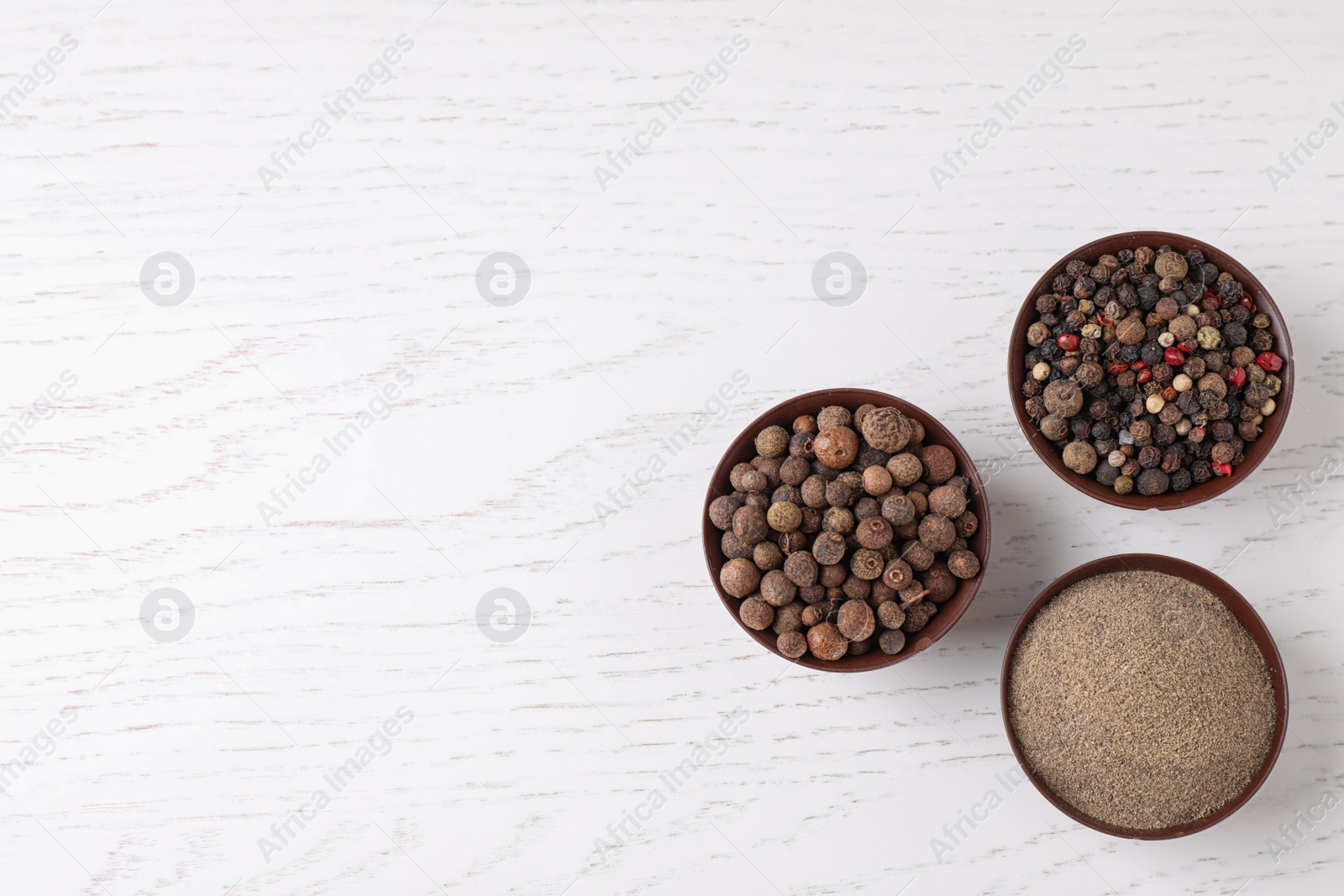 Photo of Ground pepper and corns on white wooden table, flat lay. Space for text