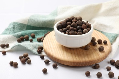 Photo of Dry allspice berries (Jamaica pepper) on white tiled table, closeup