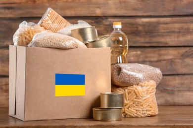 Humanitarian aid for Ukrainian refugees. Donation box with food on wooden table