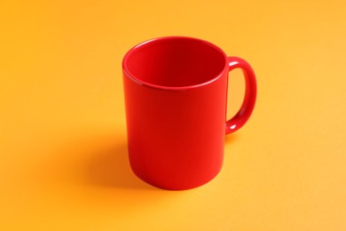 Photo of One red ceramic mug on orange background