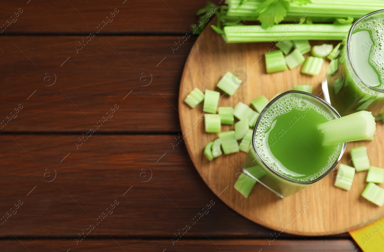 Photo of Glasses of delicious celery juice and vegetables on wooden table, flat lay. Space for text