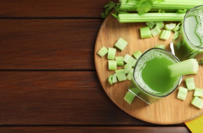 Glasses of delicious celery juice and vegetables on wooden table, flat lay. Space for text