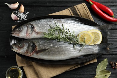 Photo of Flat lay composition with tasty sea bass fish on black wooden table