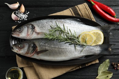 Flat lay composition with tasty sea bass fish on black wooden table