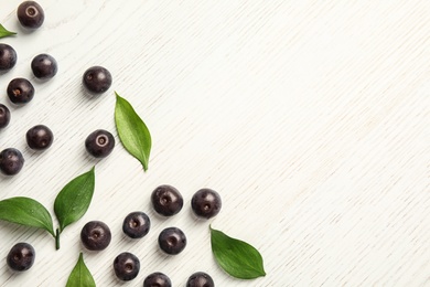 Photo of Flat lay composition with fresh acai berries and leaves on wooden background